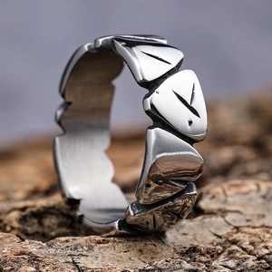 Vintage silver stainless steel Viking ring with rune engravings on bark background