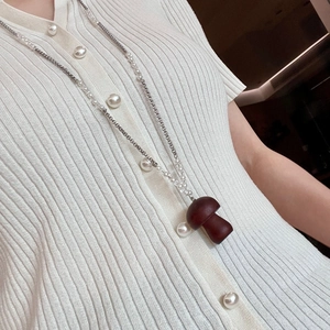 Vue détaillée du collier pendentif champignon vintage avec perles sur cardigan