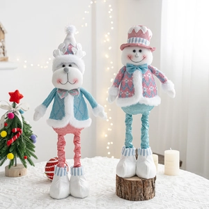 Close-up of reindeer and snowman plush dolls in soft blue and pink knitwear with lace