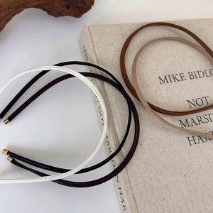 Close-up of slim faux leather headbands with fine stitching and gold metal end tips