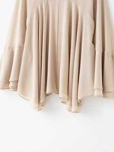 Close-up of beige chiffon top with layered ruffle hem and irregular flowy design