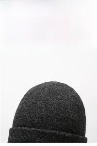 Detail of dark grey knit beanie showing thick texture and warm folded cuff design