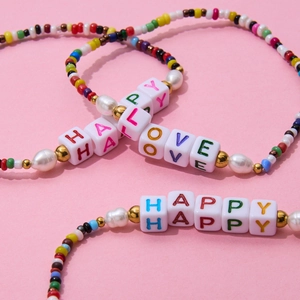 Detail of colorful beads and white pearls bracelet with HAPPY and LOVE letter charms