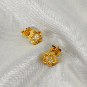 Elegante goldene Blumenstecker mit Zirkonia Kristallen auf silbernem Satinhintergrund
