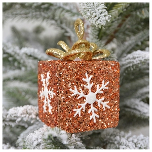 Close-up of sparkling orange glitter gift box ornament with white snowflake patterns