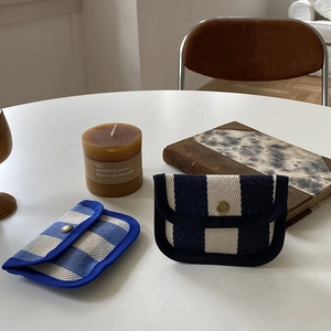 Detailed top view of striped and checkered canvas mini pouches on a minimalist table