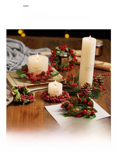 Macro detail of Christmas candle ring with red berries, pine cones and green leaves
