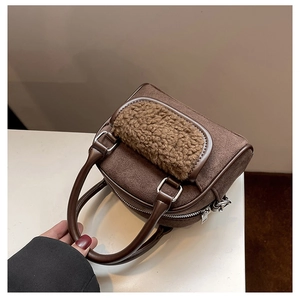 Detail of plush sheepskin patchwork on dark brown suede handbag with metal zipper