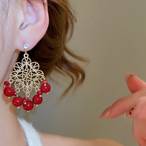 Close-up of vintage flower earrings with red beads and zircon in gold metal finish