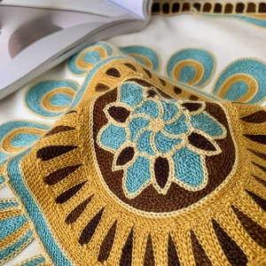 Detailed view of bohemian floral embroidered cushion cover, textured towel embroidery.