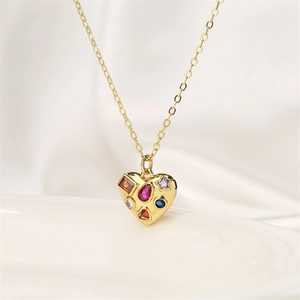 Detail of gold heart pendant with multi-colored gemstones on soft white silk background