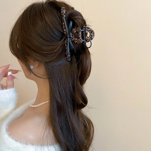Close-up of leopard print bow hair claw clip styled on brunette wavy hair for women
