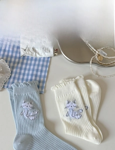 Détail de chaussettes en maille avec broderie chat et bordure en dentelle volantée