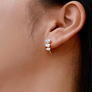 Macro shot of gold drop-shaped earrings with three tiered sparkling zircon stones on ear
