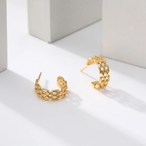 Close-up of golden S925 silver hoop earrings with a triple-row chain braided texture