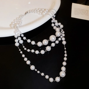 Detail of layered white pearl necklace with silver chains on a luxury black background