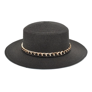 Détail d'un chapeau de paille à sommet plat avec une chaîne dorée décorative