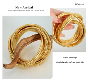 Detail of a triple-layer gold plated snake chain bracelet wrapped on a wooden branch