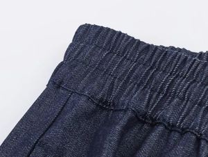 Detail of the elastic waistband on deep blue denim pants showing high quality stitching