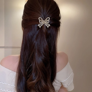 Golden hollow butterfly hair claw with pearls on long brown wavy hair for a chic look