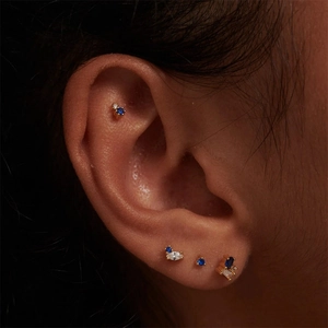 Detailed close-up of blue and clear crystal stud earrings set worn on model's ear