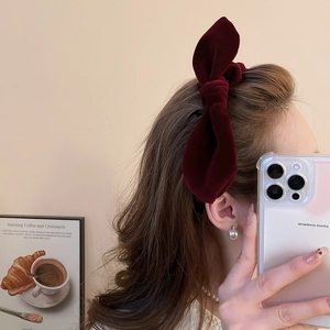 Detail view of a burgundy velvet knotted headband on a model in a cozy indoor setting