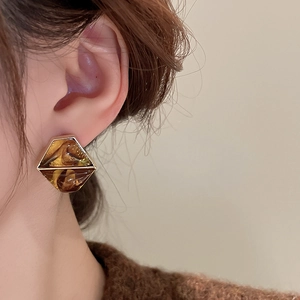 Macro side view of a model wearing a vintage amber resin hexagonal earring with gold trim