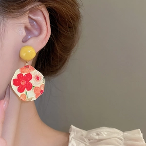 Macro shot of French artistic oil painting sunflower earrings on model's ear