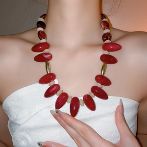 Detail of bohemian red teardrop beads and gold accents on a statement choker necklace