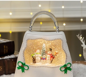 Close-up of a white handbag snow globe with snowman family and warm lighting detail