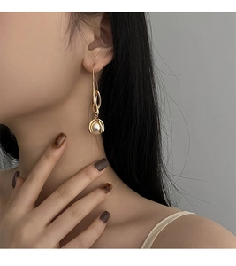 Nahaufnahme von eleganten goldenen langen Perlenohrringen, getragen von einem Modell