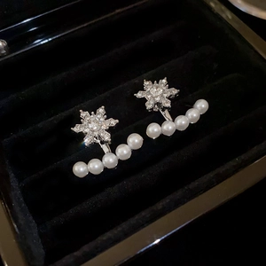 Macro detail of vintage snowflake earrings with crystals and pearls in a black jewelry box