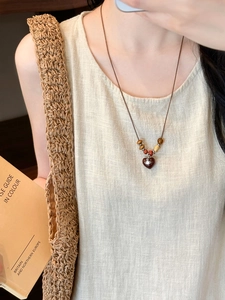 Close-up of coconut shell wood beads and heart pendant with saturn logo on necklace