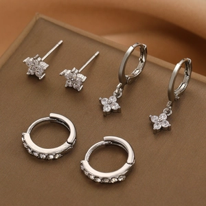 Silver star and flower earring set with zircon studs and hoops on brown leather background