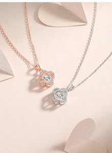 Macro shot of dancing heart clover pendants in rose gold and silver on pink background