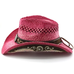 Macro detail of pink woven cowboy hat featuring floral embroidery and rhinestone band