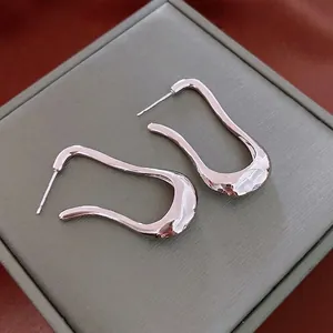 Irregular silver wavy stud earrings with minimalist curved design and metallic shine