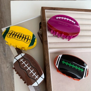 Détail de pinces à cheveux en acrylique en forme de rugby sur un plateau en bois