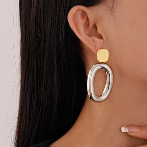 Minimalist oval geometric earrings in gold and silver finish shown on a female model