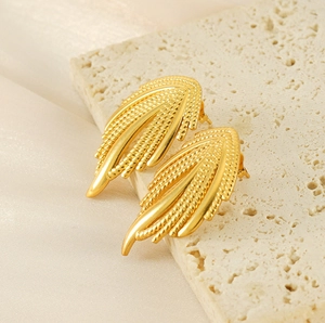 Detail of 18K gold-plated woven leaf earrings with metallic texture on silk background