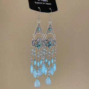 Detail of ethnic earrings with light blue bead tassels and triangle metal carving