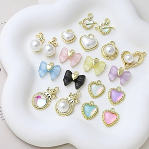 Assorted DIY heart and pearl charms in pastel colors displayed on a white tray