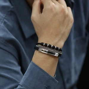 Close-up of layered black leather bracelet with metal bar and beads on male wrist