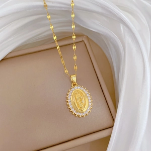 Close-up of golden oval Virgin Mary pendant with white zircon halo on a flat chain