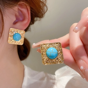 Macro detail of vintage gold square earrings featuring turquoise stones and intricate filigree