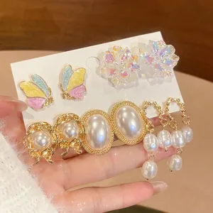 Elegant butterfly and pearl stud earring set with floral accents and iridescent details