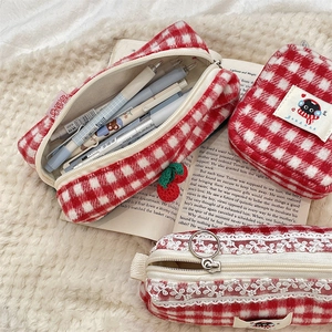 Detailed shot of checkered knit pouches with cherry charms and cat embroidery on plush fur