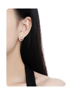 Close-up of model wearing textured silver round hollow stud earrings with sparkling diamonds