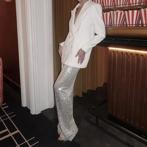 Detail of silver sequined straight-leg trousers paired with a white double-breasted blazer