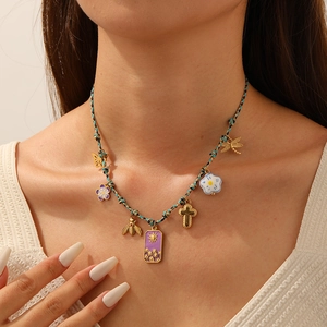 Bohemian woven rope necklace with gold bee, cross and purple enamel charms on a model